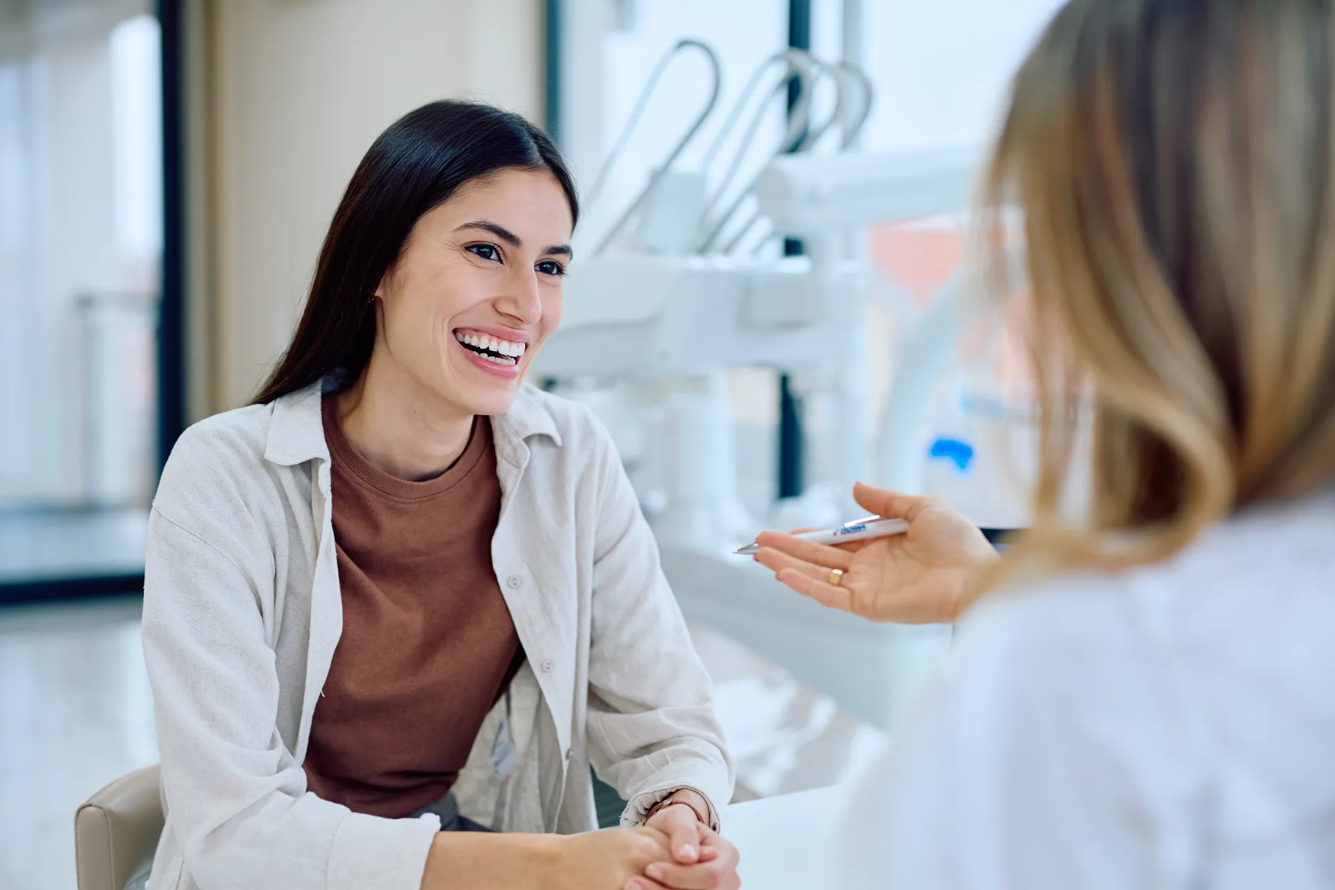A patient laughing across the desk from her clinician in a bright treatment room