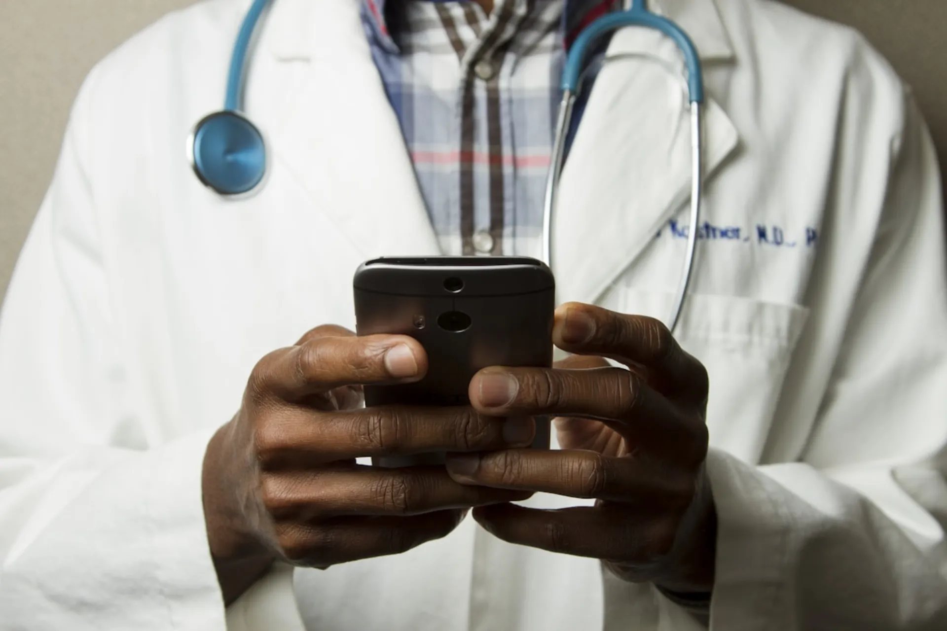 A clinician in a white coat holding a phone, mid-call